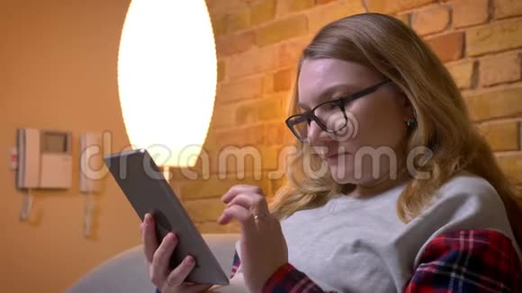 特写镜头从年轻的怀孕女性在平板电脑上浏览到她可爱的胃未来的妈妈视频的预览图