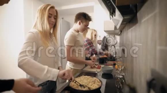 年轻人在现代厨房一起做饭两个女人在洗蔬菜另一个女孩在搅拌糊状物视频的预览图