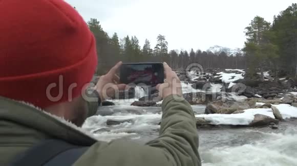 旅行者戴着红色帽子背着一个背包停下来拍了一张山河的照片旅行和视频的预览图