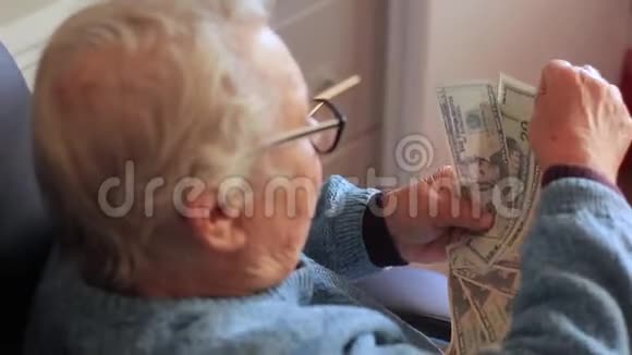 手里拿着钱的老年妇女奶奶带着美元特写视频的预览图