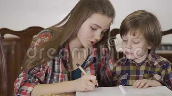 特写可爱的姐姐和可爱的弟弟学习课的肖像一个女孩做家庭作业的时候视频的预览图