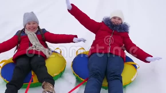 快乐的孩子少年沿着白色的雪道滚在雪盘上笑起来快乐的女孩会在冬天滑雪视频的预览图
