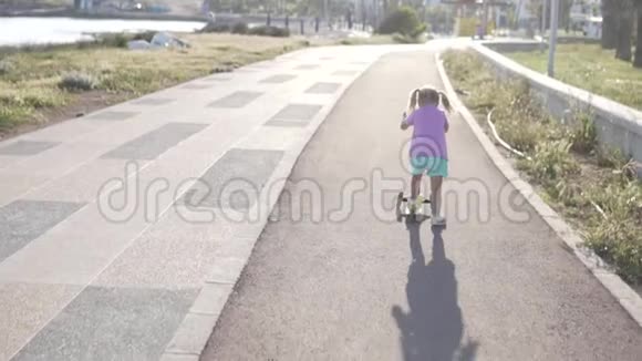 一个两条尾巴的小女孩正在海边的公园里骑摩托车视频的预览图