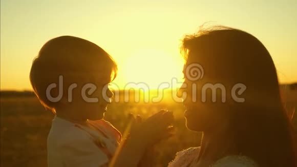 日落时分妈妈和她的小女儿在公园里玩孩子坐在母亲的怀里幸福的家庭在春天散步妈妈视频的预览图