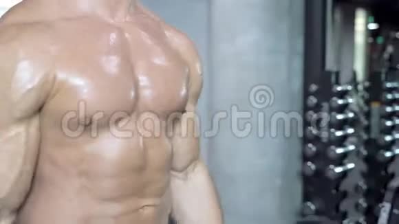 一个肌肉发达的男人赤裸的躯干在健身房锻炼视频的预览图