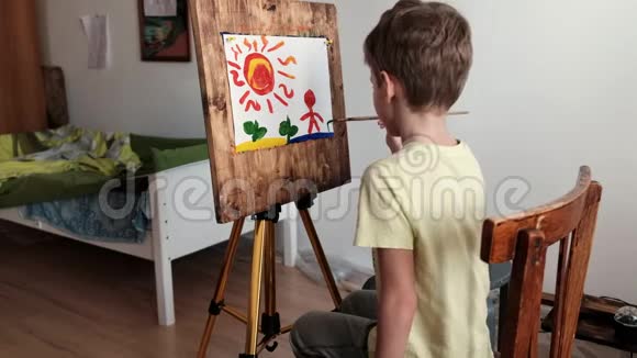 学龄前的男孩用画笔在画架上涂上水粉颜料视频的预览图