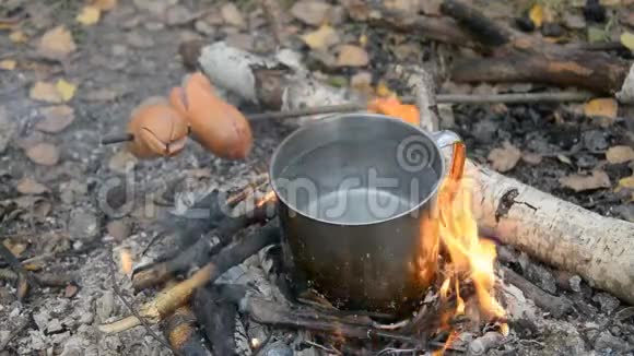 野营时做饭杯子里的水和木炭香肠视频的预览图