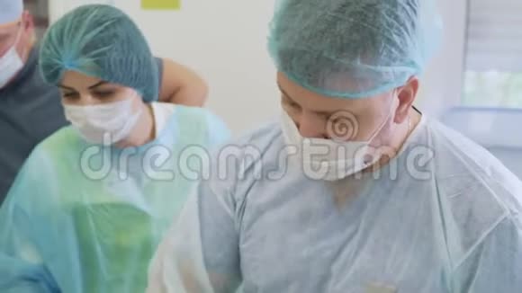 两名医生和护士在手术室手术期间戴无菌口罩和衣服的画像视频的预览图