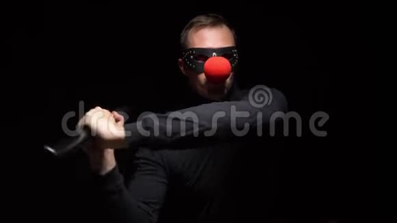 戴着红色小丑鼻子的人在黑色背景上挥舞着蝙蝠视频的预览图