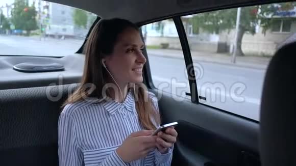 坐在出租车后座的女人听音乐使用智能手机视频的预览图