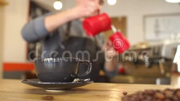 一个人在咖啡店里做一杯香浓的拿铁他倒牛奶的模糊形象视频的预览图