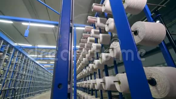在一家纺织厂用白色的线在架子上成排地切割纺织工业概念视频的预览图