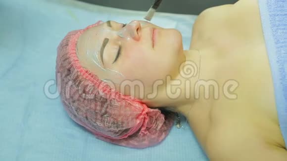 戴手套的美容师用刷子把泥面罩涂在女人脸上侧视视频的预览图