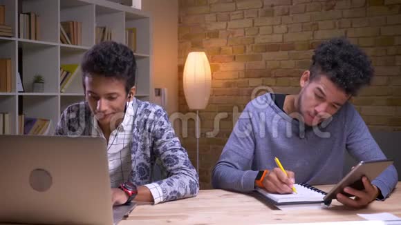 印度男性兴奋地用笔记本电脑听音乐的特写镜头非裔美国学生则使用视频的预览图