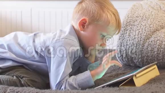 小孩子在家里的沙发上用平板电脑视频的预览图