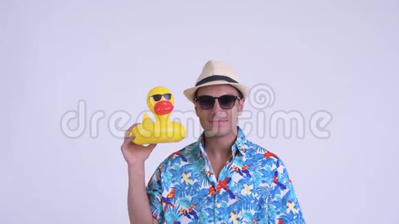 年轻快乐的西班牙游客带着太阳镜手持充气鸭的脸视频的预览图