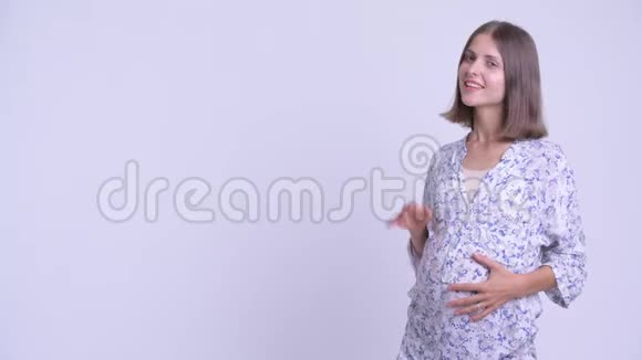 快乐的年轻孕妇摸着什么看上去很惊讶视频的预览图