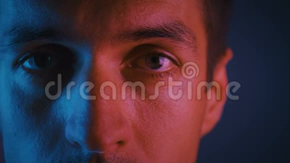 多色霓虹灯中男性的特写眼睛一个年轻人在晚会上穿着霓虹灯的肖像视频的预览图