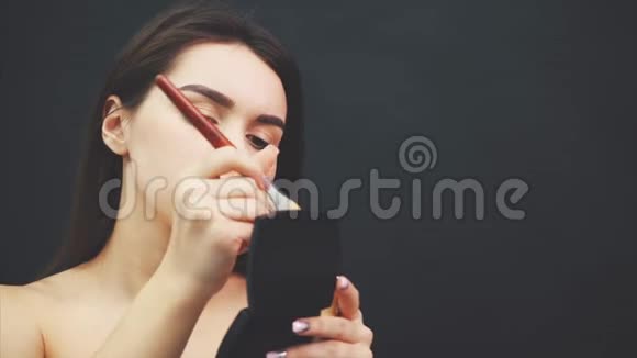 一个皮肤完美的漂亮女孩的特写在此期间在照镜子的脸上涂上粉末视频的预览图
