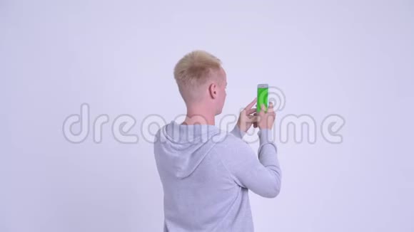 年轻金发男子用电话拍照后景视频的预览图