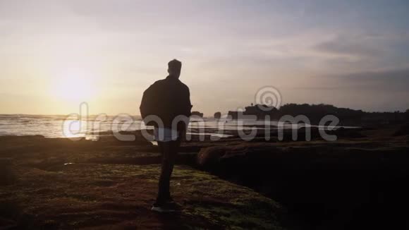 年轻人沿着海滩散步跳跃张开双臂迎接美丽的日落慢动作视频的预览图
