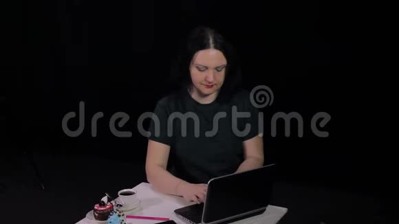 一个女人在咖啡馆的一张桌子上用电脑在键盘上打字喝着咖啡视频的预览图