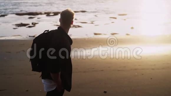 人沿着黑沙滩行走在夕阳的金光下翻转慢动作镜头耀斑视频的预览图