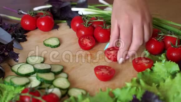 贴身女人在木切割板上切樱桃西红柿慢动作视频的预览图