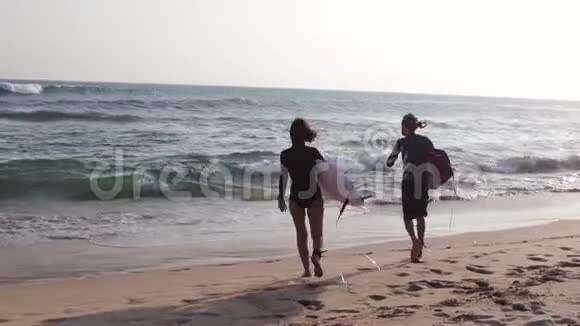 一对年轻的冲浪者带着冲浪板奔向大海视频的预览图