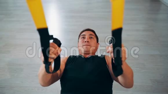一个男人在健身房里练习TRX环拉到了胸口顶推视频的预览图