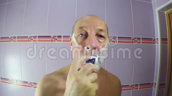 浴室里的男人用剃刀刮掉脸颊和下巴上的胡茬视频的预览图