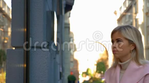 年轻迷人的金发女郎梦想着在精品店橱窗附近买新东西视频的预览图