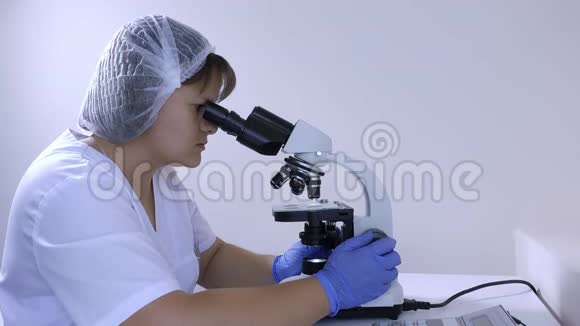 女化验员坐在工作场所做显微镜检查视频的预览图