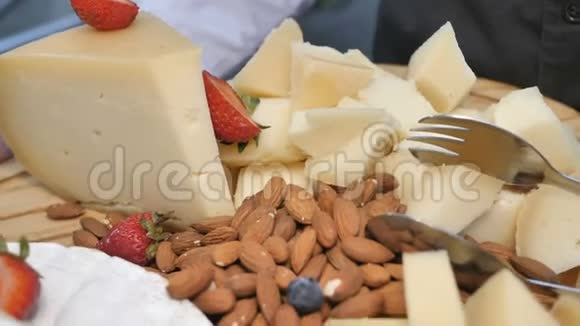 木制餐盘餐饮服务中各种奶酪片坚果浆果和招待客人的水果视频的预览图