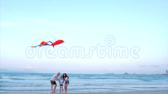 在海洋背景下父母和女儿在海洋中与年长的风筝玩耍视频的预览图