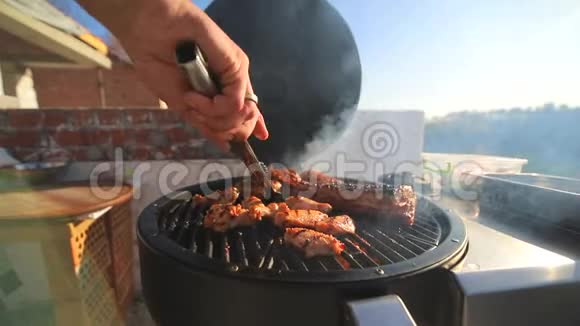 一块块肉鸡排骨火上煎厨师手翻着肉在屋顶烧烤肉视频的预览图