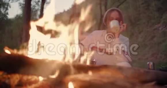 一对年轻夫妇坐在火边聊天一个男人吃棉花糖一个女孩喝茶视频的预览图