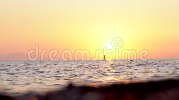 冲浪女子站在一块木板上在日落的背景下拍摄结束海浪拍打镜头视频的预览图