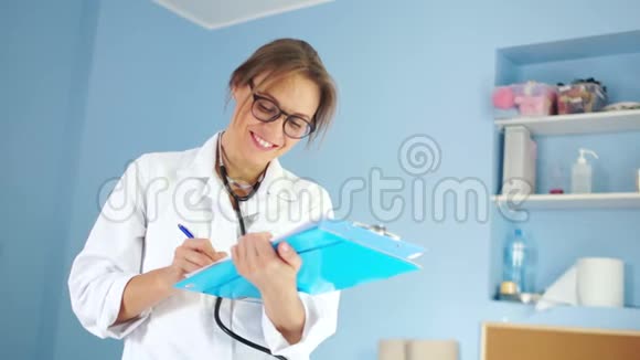 穿着白色医用外套和听筒的女医生看着镜框用白牙微笑视频的预览图