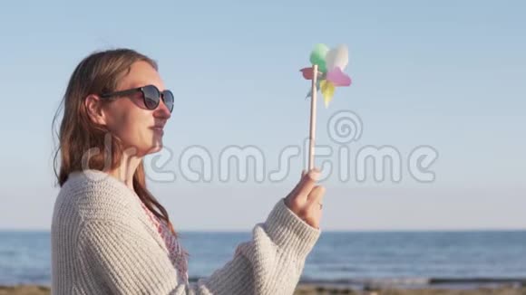 夏日假期戴太阳镜的美女玩玩具风车视频的预览图