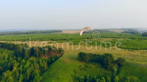 一个人用滑翔机飞过绿树滑翔伞动作极限运动理念视频的预览图