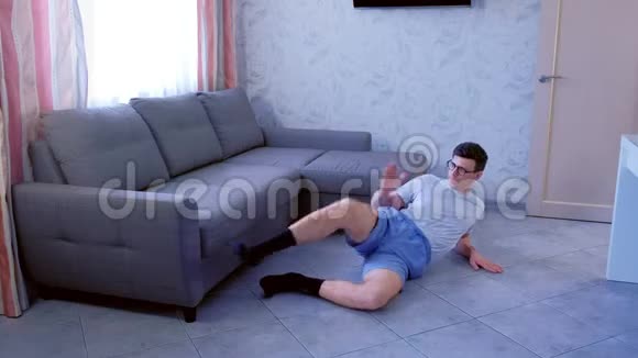 疯狂的书呆子在家里为躺在地板上的腿做有趣的整形练习体育幽默概念视频的预览图