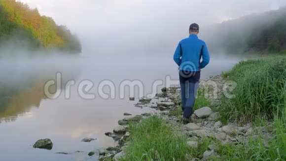 男人带着石头走过碧水沿着河岸走视频的预览图