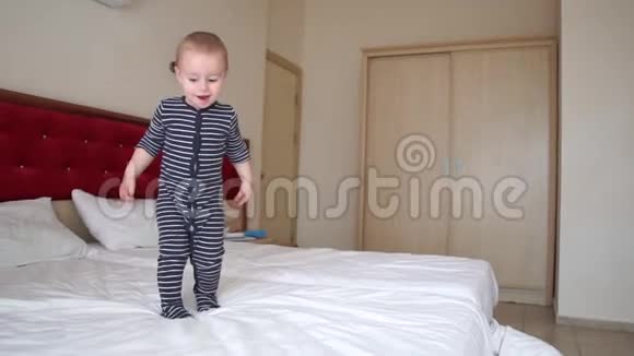 可爱的金发幼儿快乐地在旅馆房间的大床上缓慢地跳跃视频的预览图