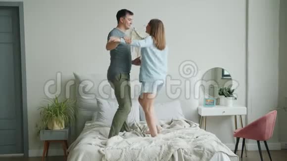 可爱的幸福夫妇在家里床上跳舞手牵着手玩得开心视频的预览图
