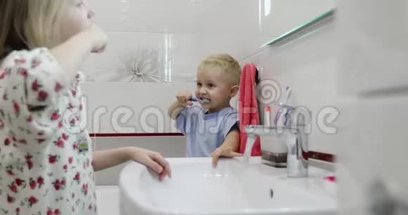 一对穿着睡衣的兄妹在浴室镜子前刷牙视频的预览图