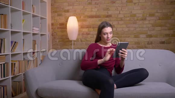 年轻美丽的黑发女性自由职业者与平板电脑集中在家里视频的预览图