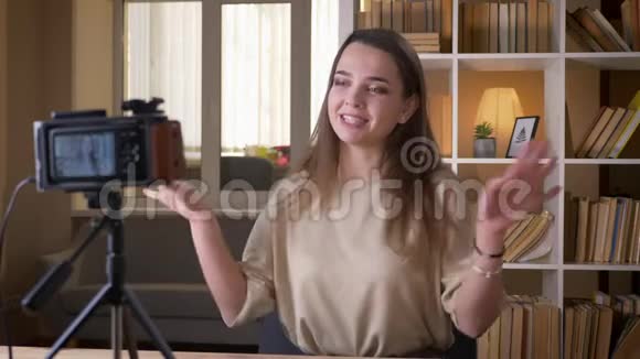 年轻有魅力的白种人女博客写手在室内的公寓里用相机愉快地交谈视频的预览图