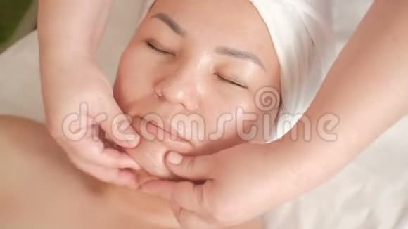 美容院中年亚洲妇女面部按摩特写镜头美容师双手手指的移动视频的预览图