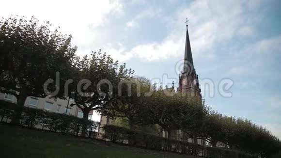 哥特式风格的旧教堂有尖顶和时钟前景是树木视频的预览图